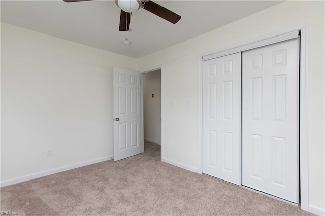 unfurnished bedroom with ceiling fan, light colored carpet, and a closet