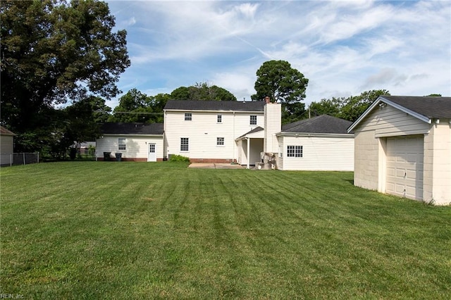 back of house featuring a yard, a garage, and an outdoor structure