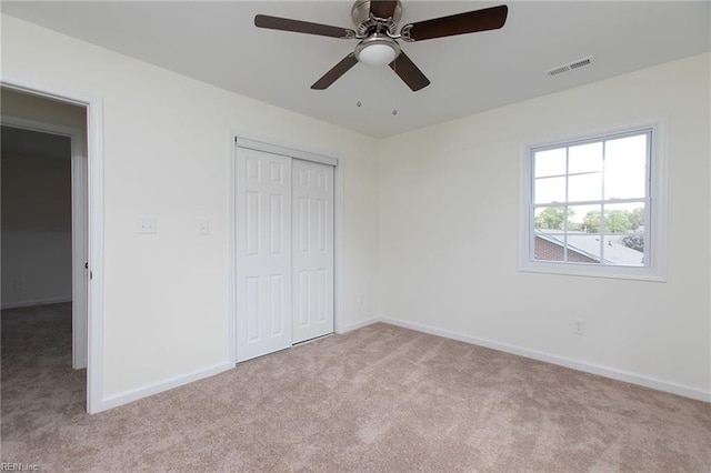 unfurnished bedroom featuring ceiling fan, a closet, and light carpet