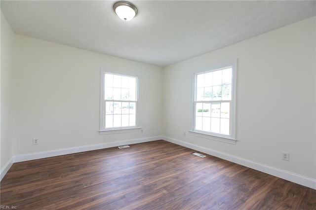 unfurnished room featuring dark wood-type flooring and a wealth of natural light