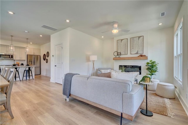 living room featuring light hardwood / wood-style flooring and ceiling fan