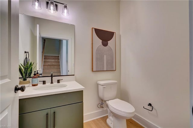 bathroom with toilet, vanity, and hardwood / wood-style flooring