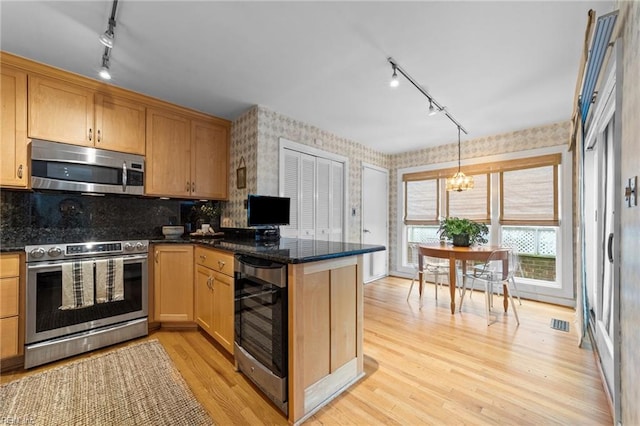 kitchen featuring rail lighting, wine cooler, dark stone countertops, light hardwood / wood-style floors, and appliances with stainless steel finishes