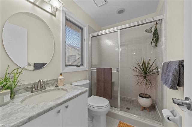 bathroom with tile patterned flooring, a shower with door, vanity, and toilet