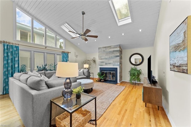 living room with ceiling fan, high vaulted ceiling, wood-type flooring, a tiled fireplace, and wood ceiling