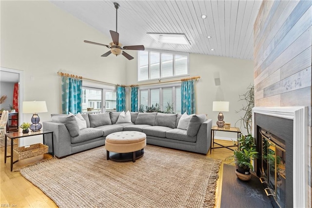 living room with wooden ceiling, a tile fireplace, high vaulted ceiling, ceiling fan, and light hardwood / wood-style floors