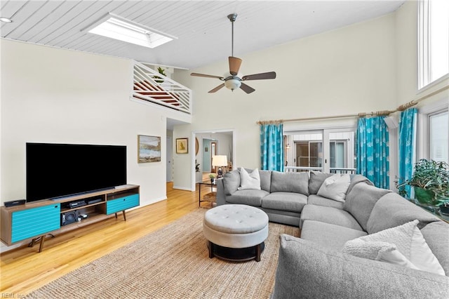 living room featuring ceiling fan, a towering ceiling, and wood-type flooring