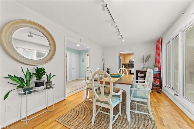 dining area with light hardwood / wood-style floors and rail lighting