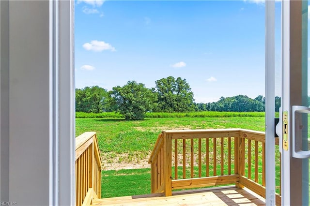 wooden deck featuring a lawn and a rural view