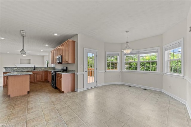 kitchen with kitchen peninsula, appliances with stainless steel finishes, light stone countertops, ceiling fan, and hanging light fixtures