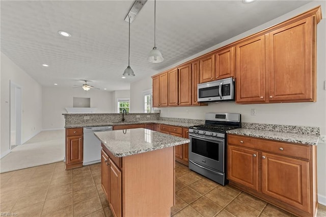 kitchen featuring sink, ceiling fan, appliances with stainless steel finishes, decorative light fixtures, and kitchen peninsula