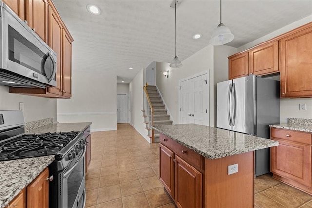 kitchen with hanging light fixtures, light stone countertops, light tile patterned floors, a kitchen island, and stainless steel appliances