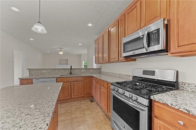 kitchen featuring light stone countertops, appliances with stainless steel finishes, ceiling fan, sink, and pendant lighting