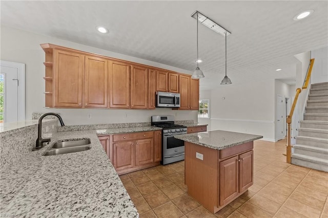 kitchen featuring a center island, sink, light stone countertops, appliances with stainless steel finishes, and decorative light fixtures