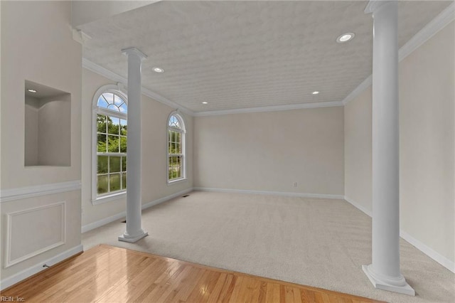 spare room with ornate columns, light hardwood / wood-style floors, and ornamental molding