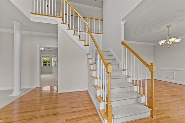 stairs with a notable chandelier, ornate columns, and crown molding