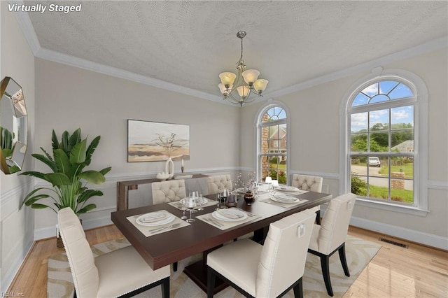 dining area featuring plenty of natural light, light hardwood / wood-style floors, a textured ceiling, and a notable chandelier