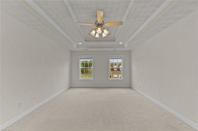 empty room featuring a tray ceiling, ceiling fan, crown molding, and light colored carpet