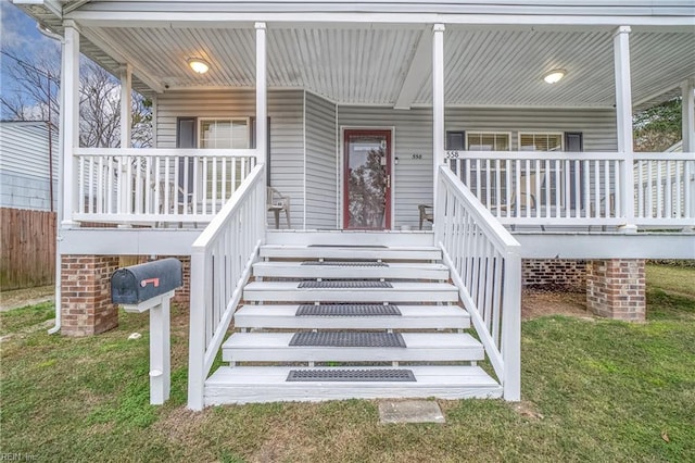 doorway to property with a lawn and covered porch