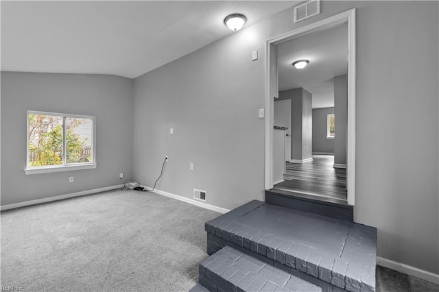 carpeted empty room featuring vaulted ceiling