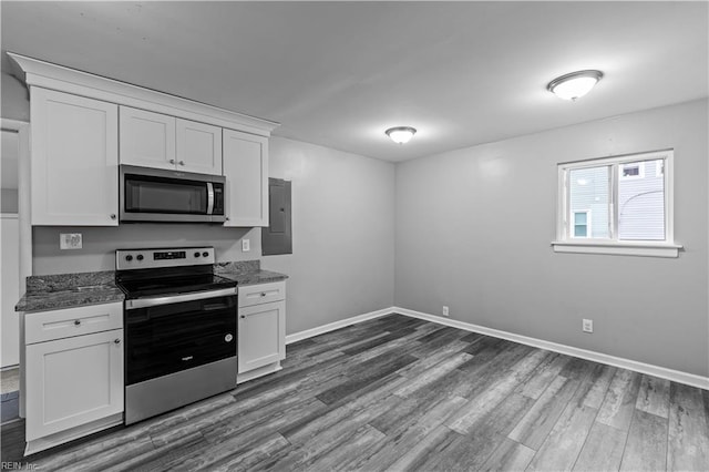 kitchen with white cabinets, dark hardwood / wood-style floors, stainless steel appliances, and dark stone counters