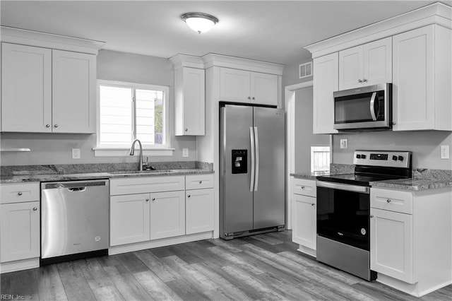 kitchen featuring appliances with stainless steel finishes, light hardwood / wood-style floors, and white cabinetry