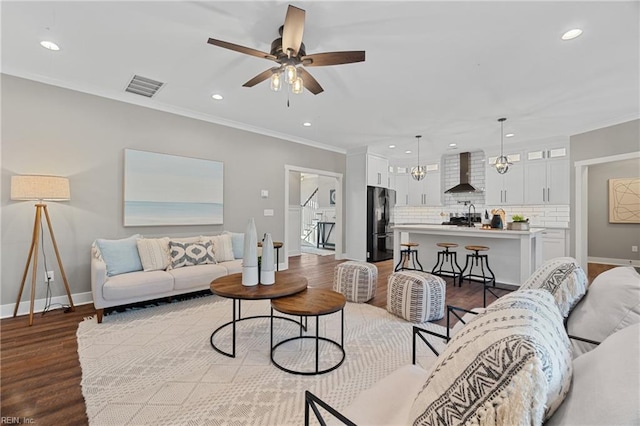 living room featuring hardwood / wood-style floors, ceiling fan, ornamental molding, and sink