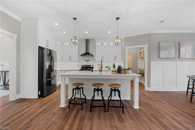 kitchen featuring stainless steel appliances, dark wood-type flooring, wall chimney range hood, white cabinets, and hanging light fixtures