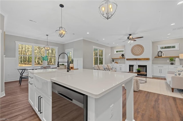 kitchen with dishwasher, a fireplace, a healthy amount of sunlight, and an island with sink