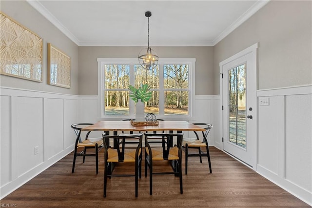 dining area with a notable chandelier, ornamental molding, and dark wood-type flooring