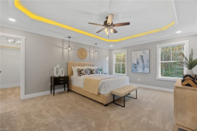 carpeted bedroom with ceiling fan, a raised ceiling, ornamental molding, and multiple windows