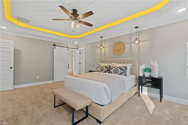 carpeted bedroom featuring a tray ceiling, a barn door, ceiling fan, and crown molding