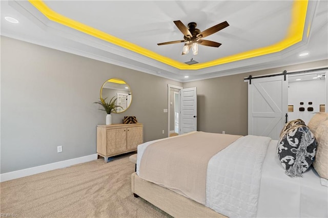 bedroom featuring carpet, ceiling fan, a barn door, ornamental molding, and a tray ceiling