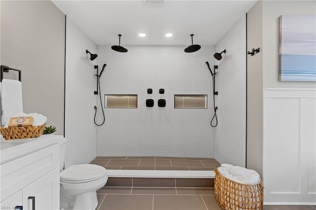 bathroom with tile patterned floors, vanity, a tile shower, and toilet