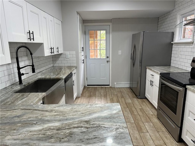 1049 Brandon Ave, Norfolk, VA 23507 - kitchen with stainless steel appliances, light stone countertops, light wood-style flooring, white cabinetry, and tasteful backsplash
