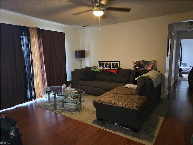 living room featuring ceiling fan, wood-type flooring, and a textured ceiling