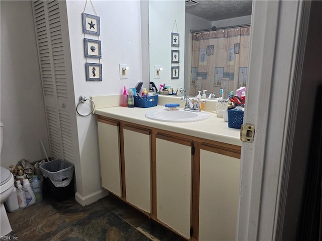 bathroom with vanity, a textured ceiling, and toilet