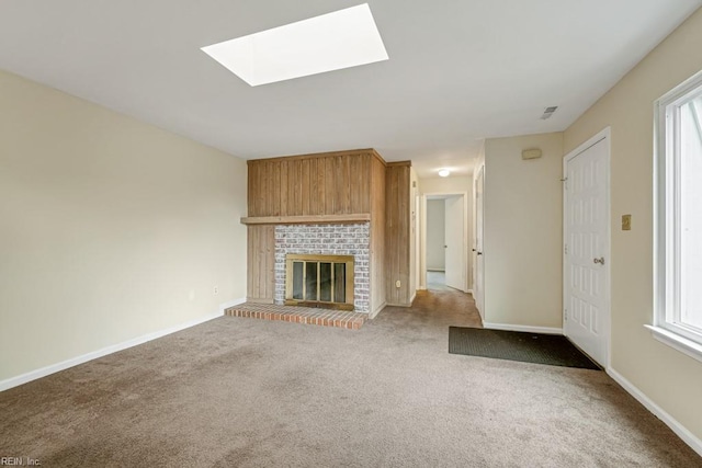 unfurnished living room with a fireplace, carpet flooring, a skylight, and a wealth of natural light