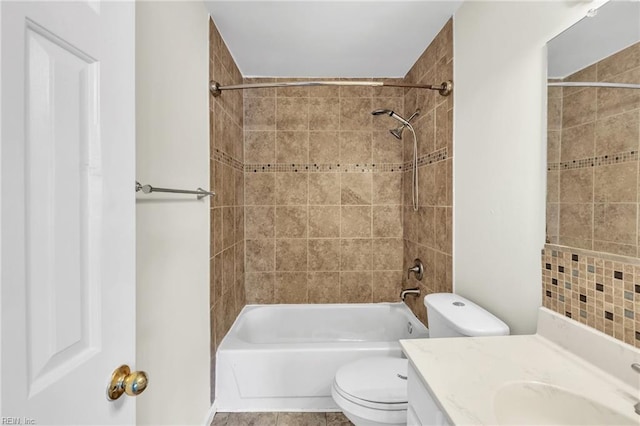 full bathroom with tile patterned flooring, vanity, tiled shower / bath combo, and toilet