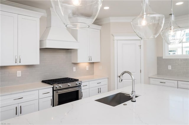 kitchen with premium range hood, sink, stainless steel gas range, ornamental molding, and white cabinetry