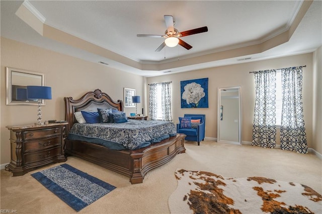 carpeted bedroom with ceiling fan, crown molding, and a tray ceiling