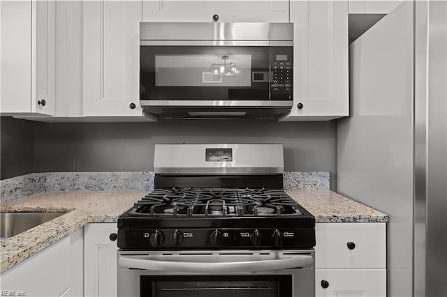 kitchen featuring light stone counters, white cabinetry, and stainless steel appliances