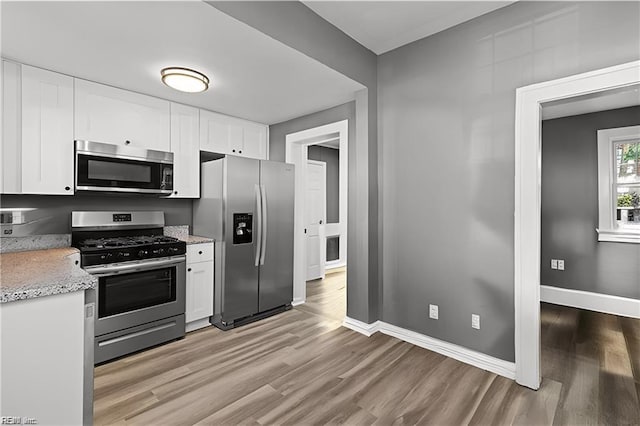 kitchen with white cabinetry, appliances with stainless steel finishes, and light hardwood / wood-style flooring