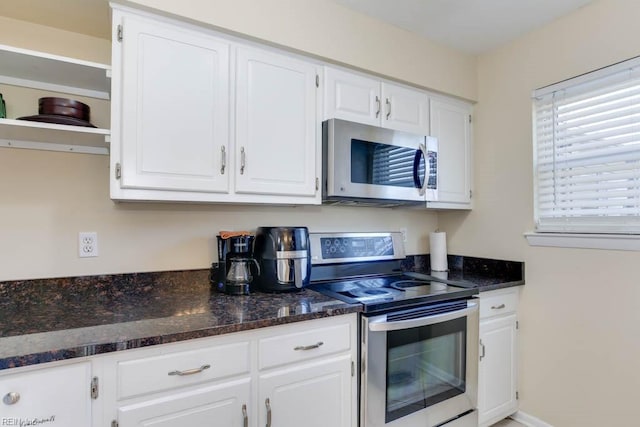 kitchen with appliances with stainless steel finishes, white cabinetry, and dark stone counters