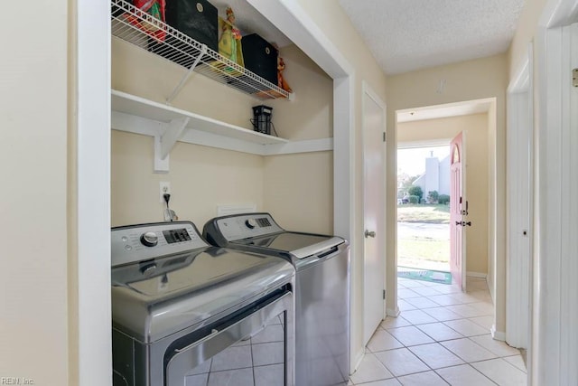 laundry room with washer and dryer, a textured ceiling, and light tile patterned flooring