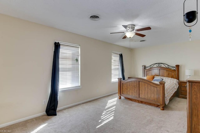 bedroom with ceiling fan, light colored carpet, and a textured ceiling