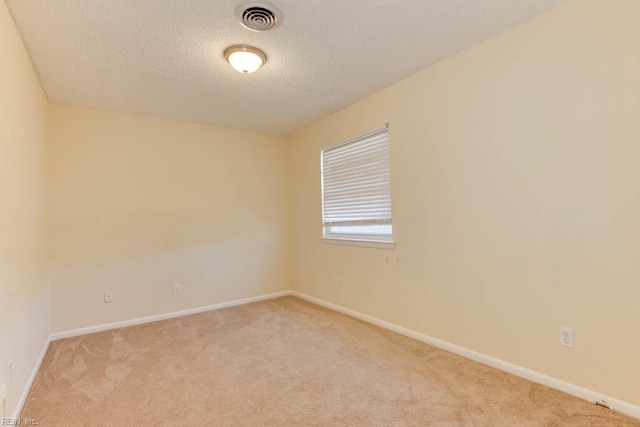 spare room with light colored carpet and a textured ceiling