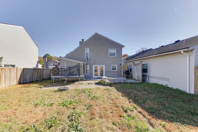 rear view of property with a lawn, a patio, and a trampoline