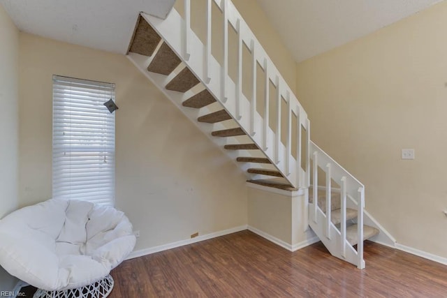 staircase featuring wood-type flooring and lofted ceiling