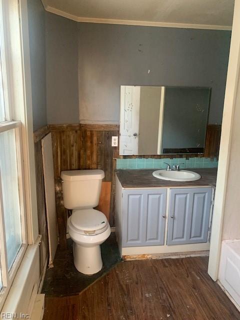 bathroom with toilet, crown molding, wood-type flooring, vanity, and a washtub